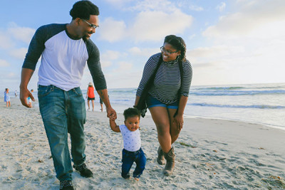Young Black family walking along a beach on vacation